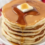 Fluffy gluten-free sourdough pancakes served with syrup and fresh berries.