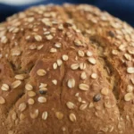 Loaf of gluten free multigrain bread with seeds, showcasing its soft texture and crispy crust.