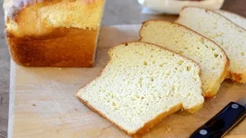 Loaf of delicious gluten free honey white bread on a wooden cutting board.