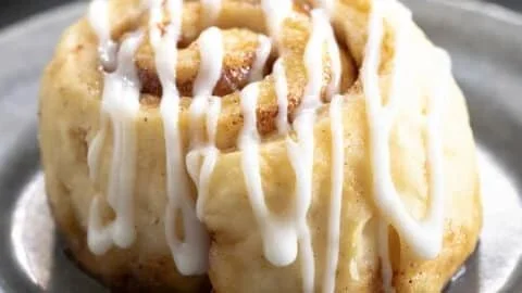 Homemade gluten-free cinnamon rolls topped with icing on a plate