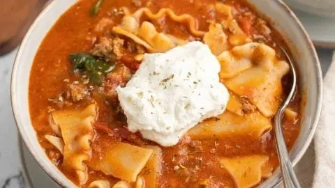 Bowl of gluten-free lasagna soup topped with fresh herbs and cheese alternatives