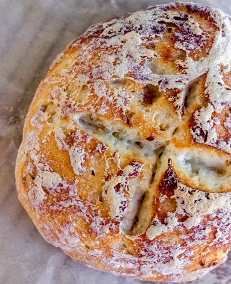 Freshly baked no-knead gluten-free bread on a wooden cutting board.